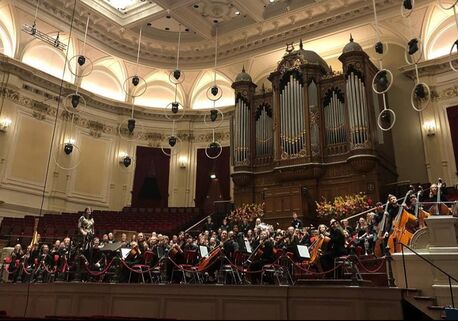 Orkest in een concertzaal met orgel tijdens een tour